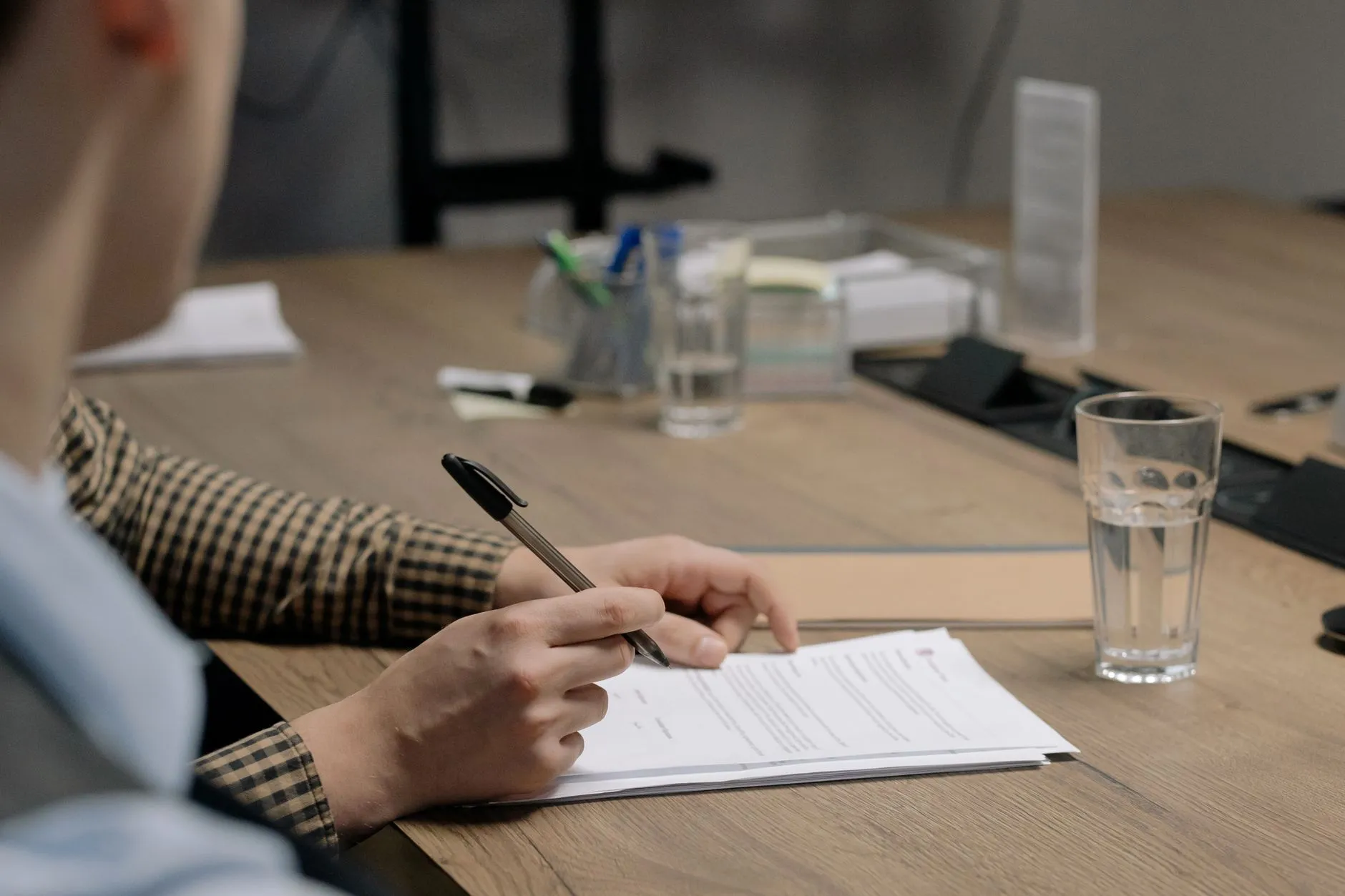 Persona revisando y firmando un documento sobre el escritorio de su oficina.