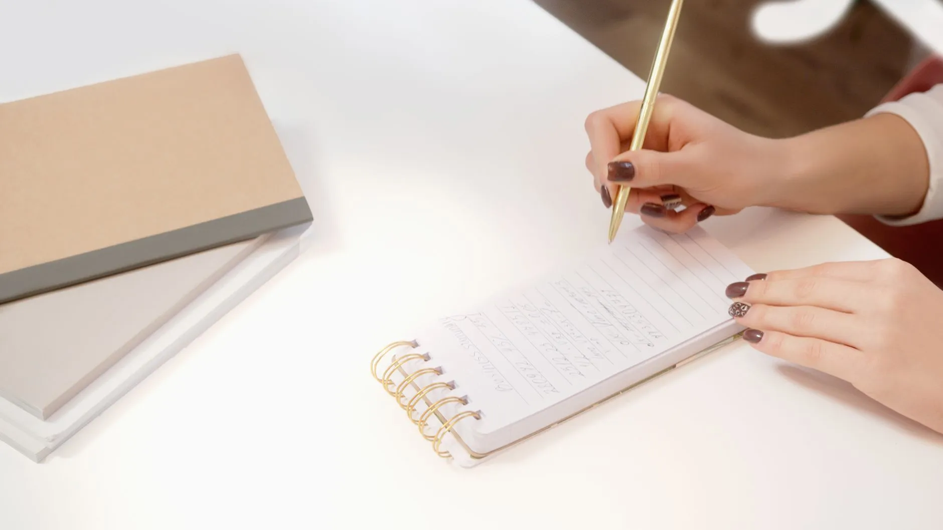 Manos escribiendo en una libreta los datos de la ficha de identificación de un paciente nuevo.