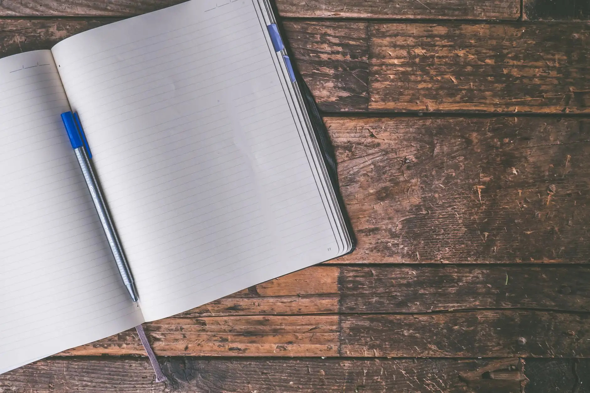 Cuaderno abierto y pluma sobre un escritorio, listo para abrir la ficha de identificación de un nuevo paciente.