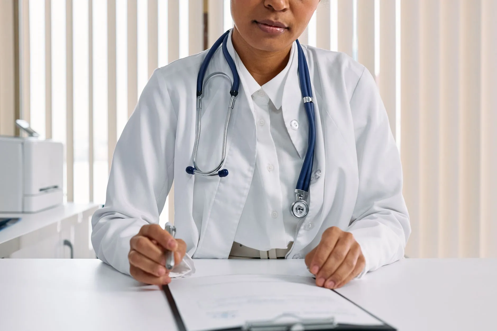 Profesional de la salud escribiendo una nota clínica con el formato SOAP en una tabla de apuntes.