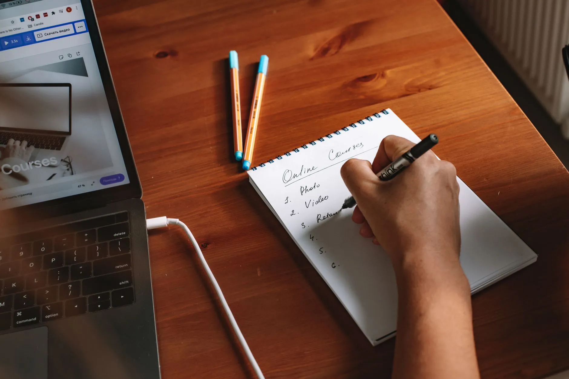 Manos escribiendo un ejemplo de caso clínico psicológico junto a una laptop en el escritorio.
