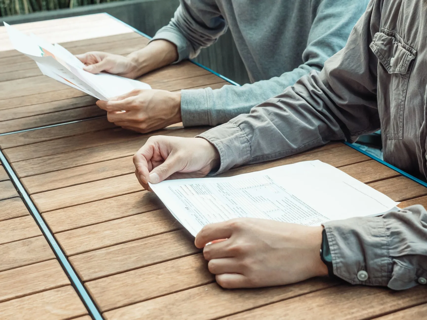 Dos personas revisan documentos distintos sobre una mesa: contrato terapéutico y consentimiento informado.