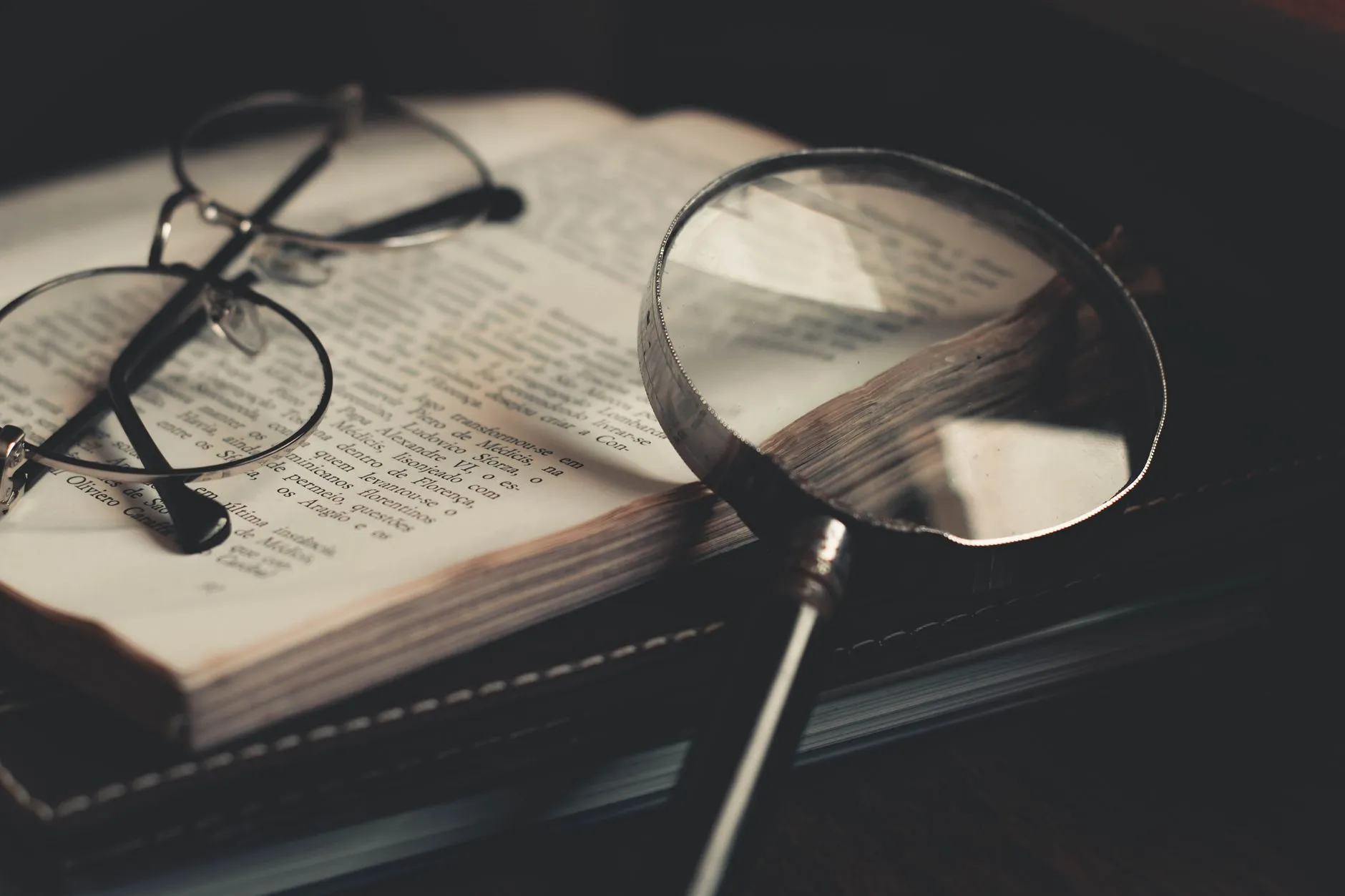 Lupa sobre las páginas de un libro abierto, como al examinar las distintas corrientes psicológicas.
