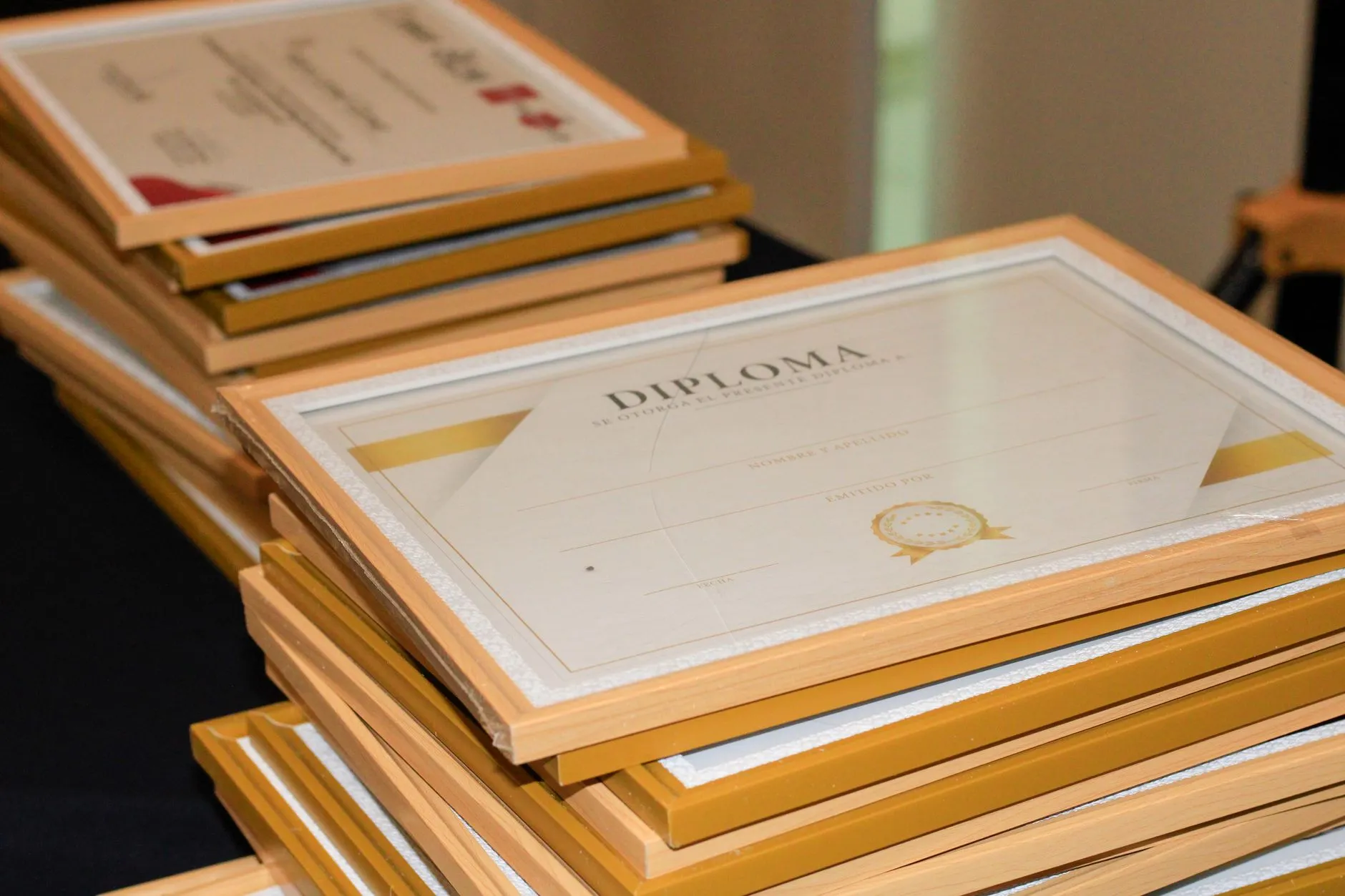 Diplomas enmarcados apilados, que representan la formación y la cédula profesional en el CV de un psicólogo.
