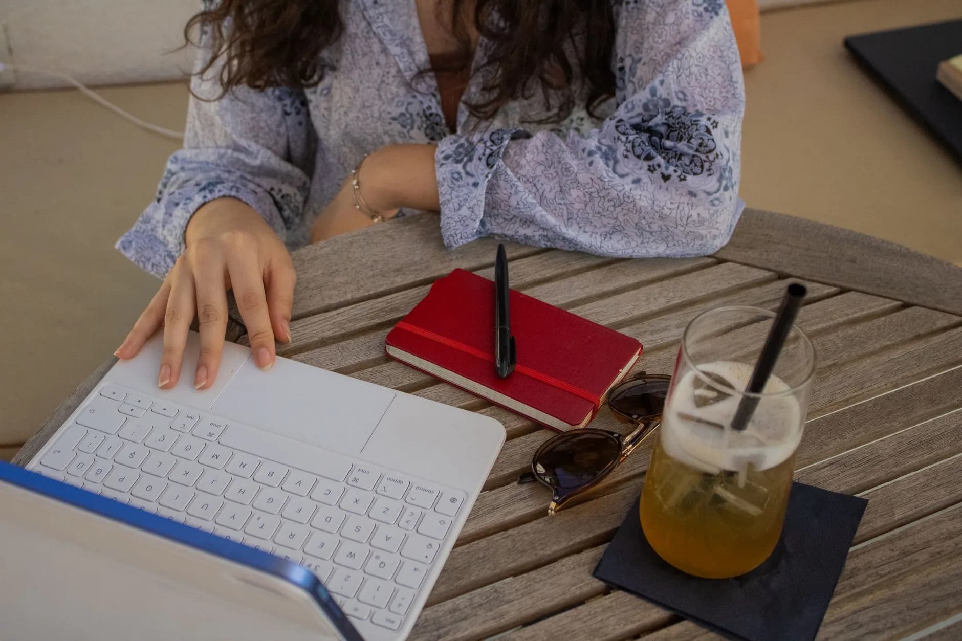 Psicóloga escribiendo su perfil profesional en una laptop junto a una libreta roja.