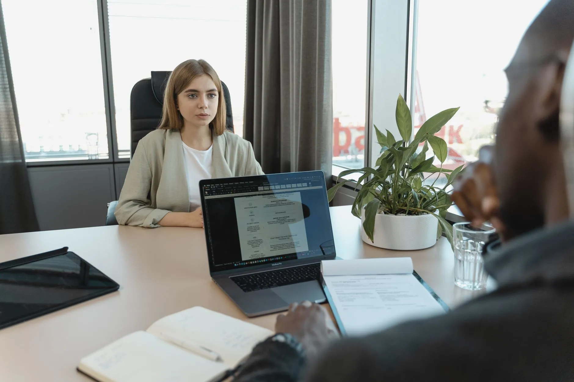 Psicóloga en una entrevista de trabajo frente a una laptop, con su currículum vitae de psicólogo sobre la mesa.