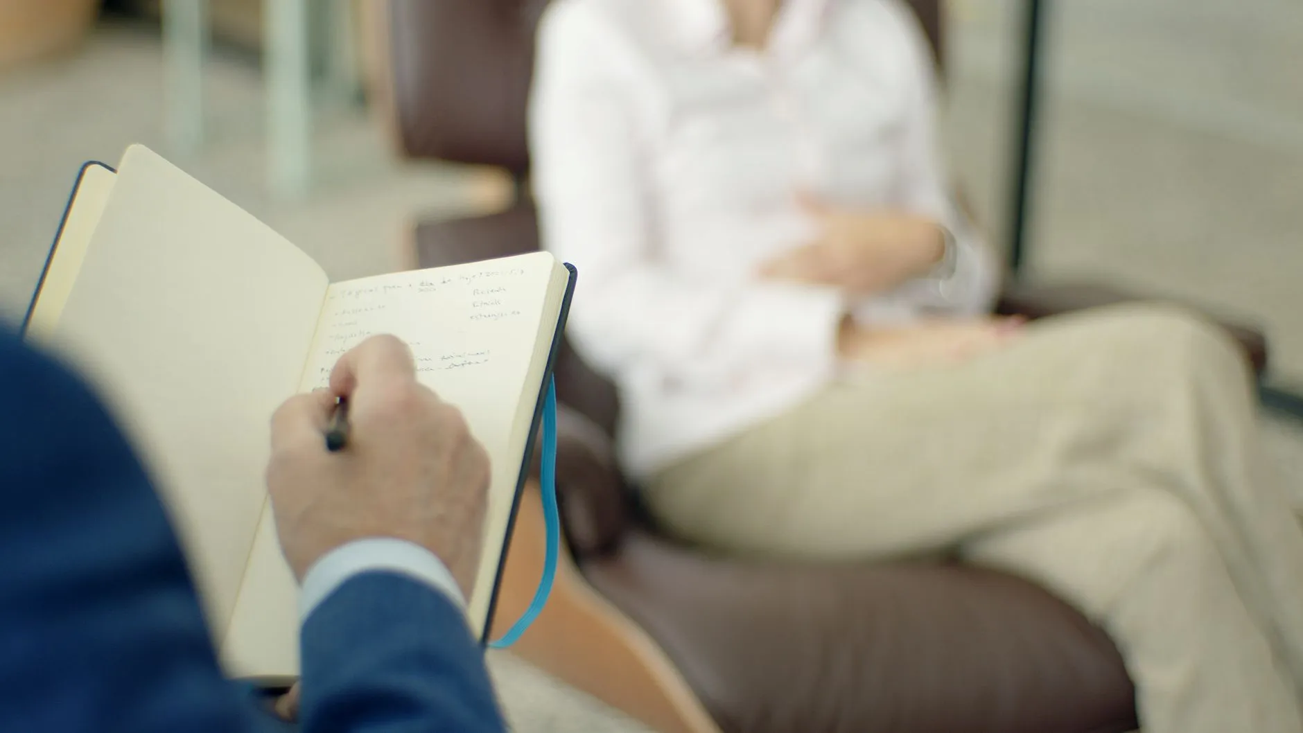 Psicólogo anota en su libreta durante la entrevista, parte de hacer un examen mental paso a paso.