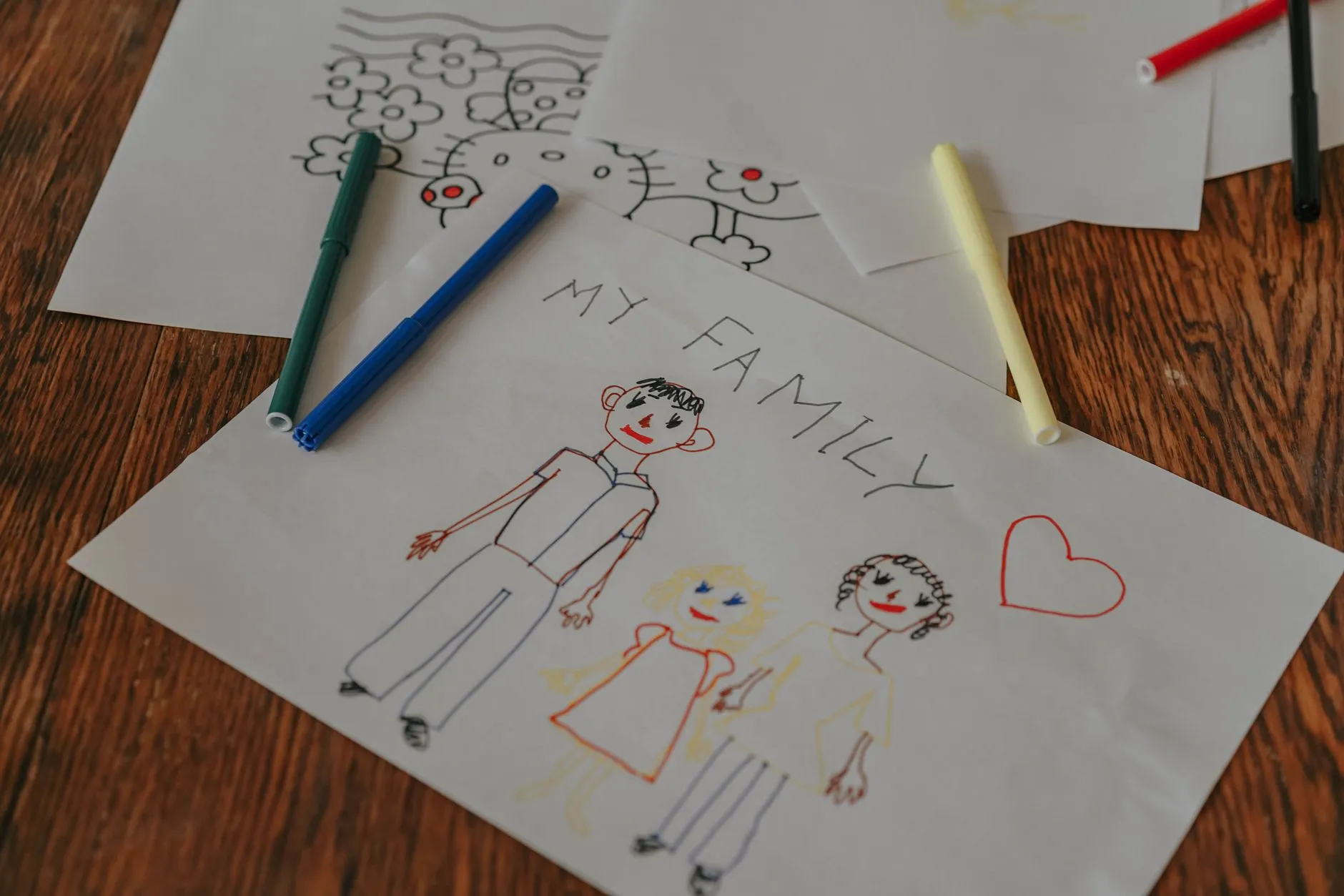 Dibujo de una familia hecho con colores sobre una mesa, que evoca el genograma y otras técnicas de la terapia sistémica.