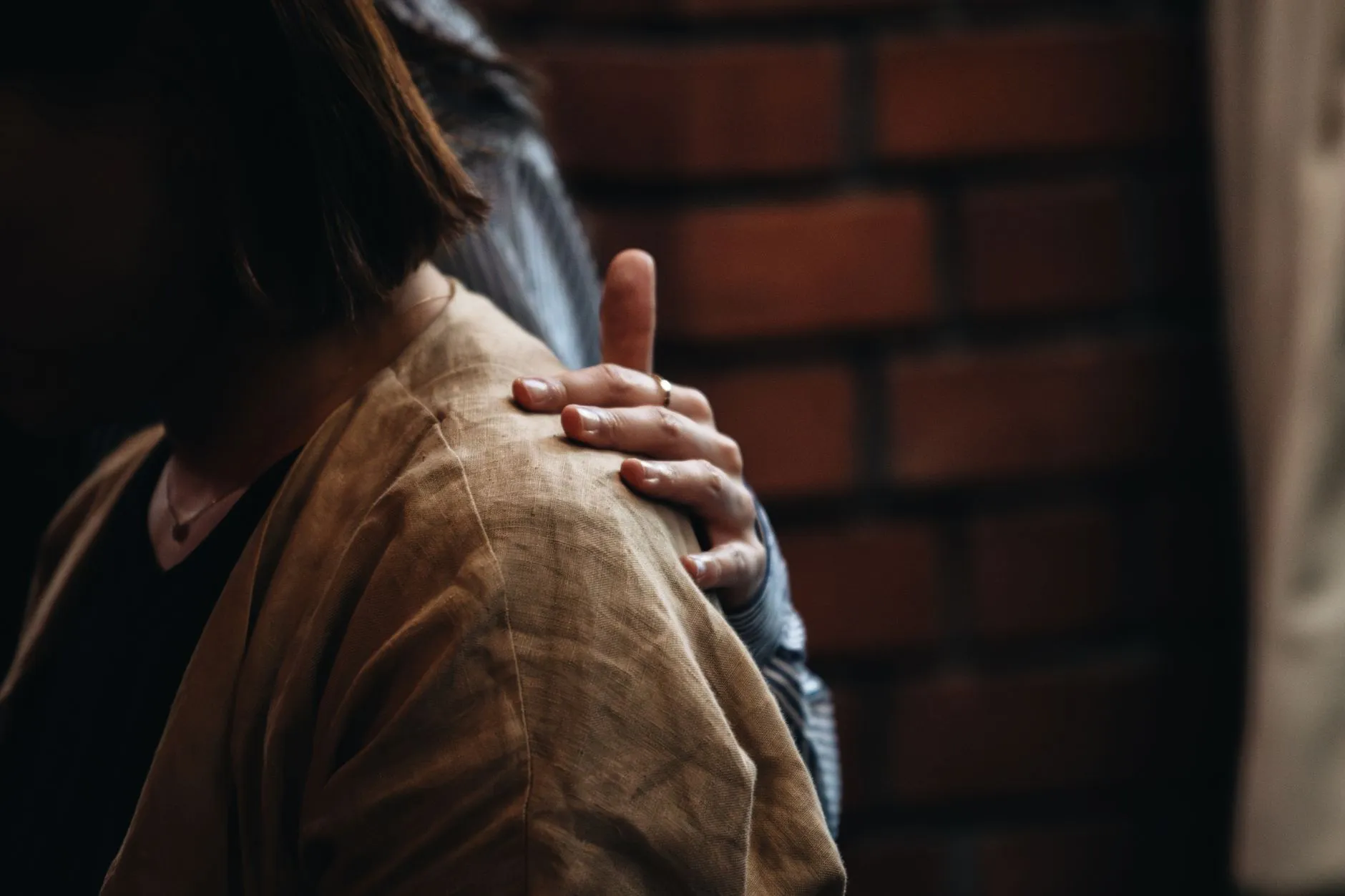 Una mano se apoya con calidez en el hombro de otra persona, en un gesto de contención emocional.