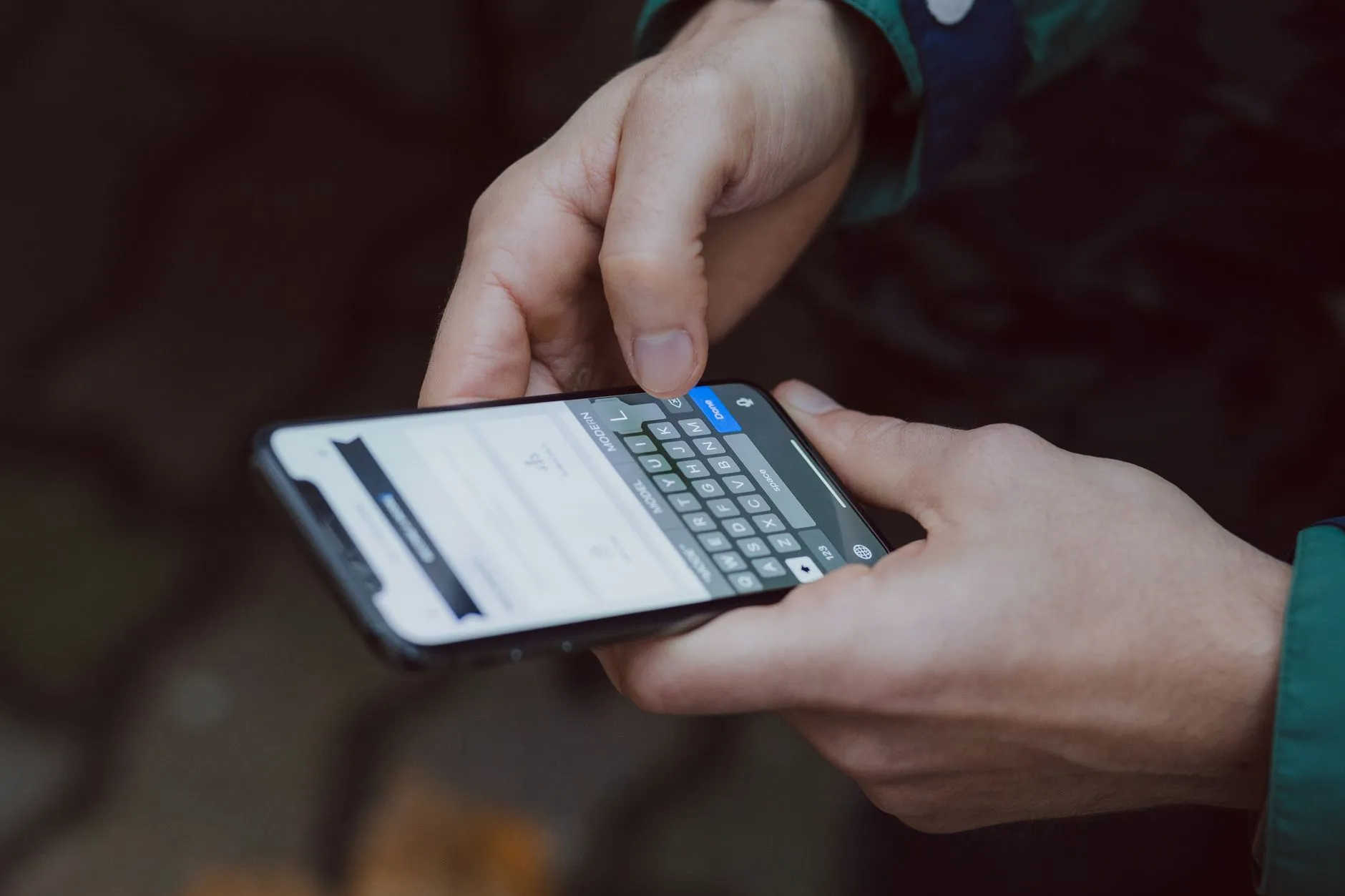 Manos escribiendo un mensaje de texto en un celular para enviarlo por WhatsApp.