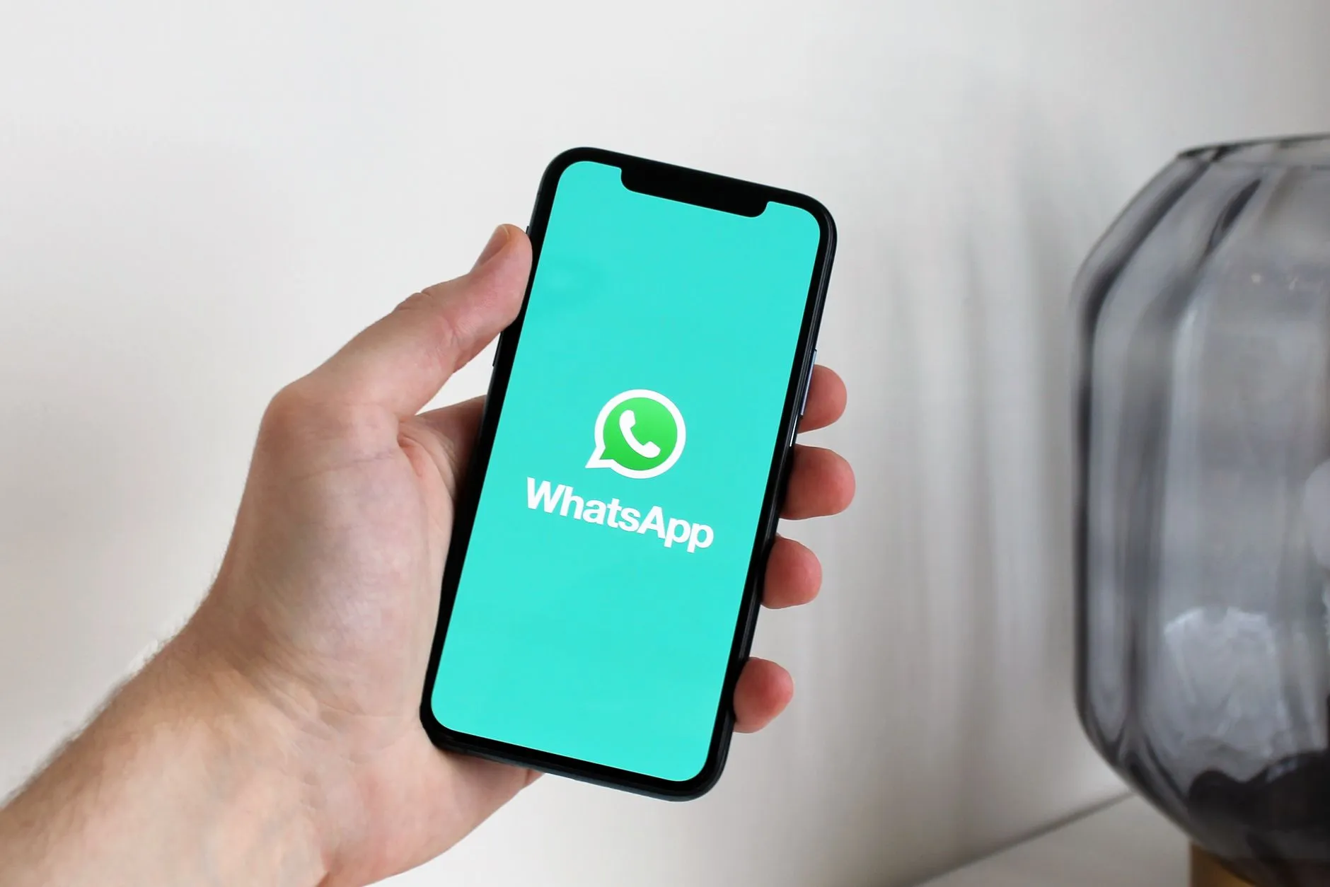 Mano sosteniendo un celular con WhatsApp abierto, listo para enviar un recordatorio de cita a un paciente.