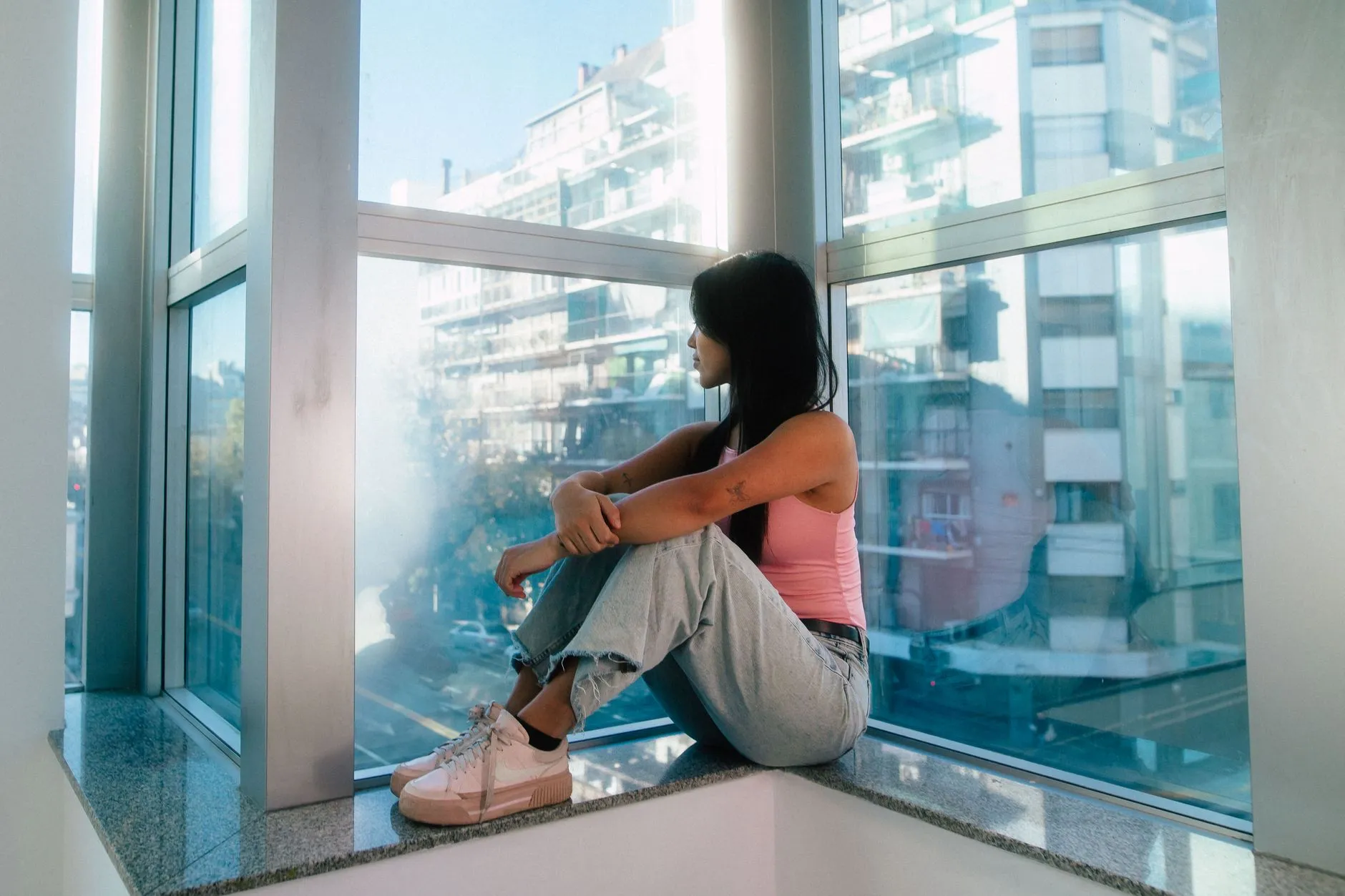 Mujer pensativa sentada junto a una ventana, reflejo del malestar que motiva buscar un tratamiento psicológico.